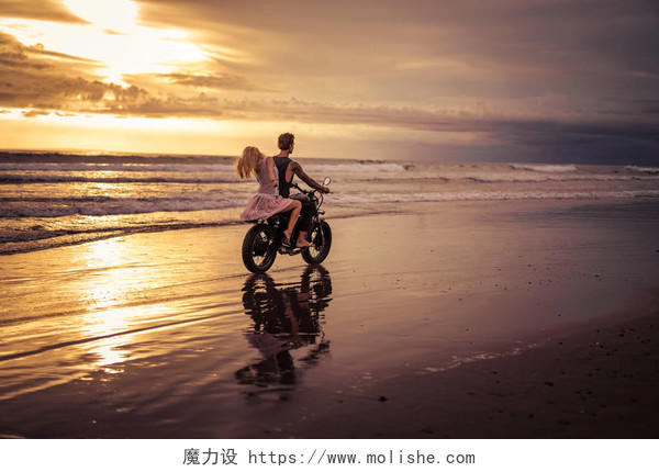 日出时男友和女友在海边骑摩托车的后视图幸福婚姻情侣幸福情侣幸福的人